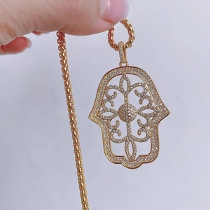 Macro shot of gold Hamsa Hand pendant with cubic zirconia inlay and hollow details