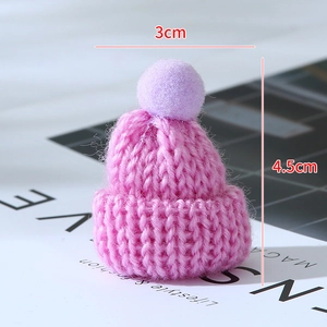 Macro shot of a pink knitted mini doll hat with purple pompom and 3x4.5cm size markings