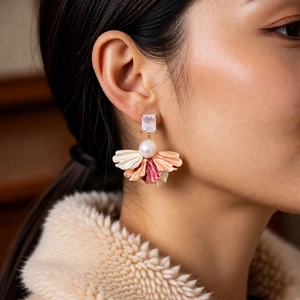 Détail de boucles d'oreilles vintage dorées avec perle et pétales dégradés roses