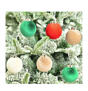 Close-up of velvet Christmas ball ornaments hanging on snowy pine branches in diverse colors