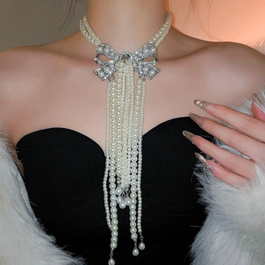 Détail d'un collier de perles avec pendentif nœud à franges et strass étincelants
