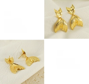 Detailed macro view of 18K gold fish tail earrings with polished texture and scale patterns