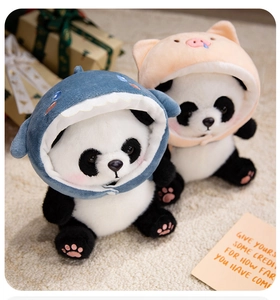 Detail of plush panda dolls wearing blue shark and pink pig hoodies on soft carpet