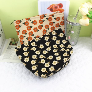 Close-up of corduroy makeup bags with floral patterns and zipper closure on a white mat