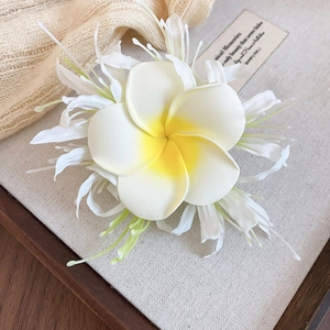 Gros plan sur une pince à cheveux élégante avec fleur de frangipanier en tissu blanc
