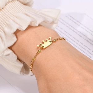 Close-up of golden crown bracelet with heart-shaped links on a model's wrist