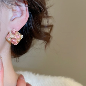 Elegant gold-plated rhombic stud earrings with pink enamel flower on a female model
