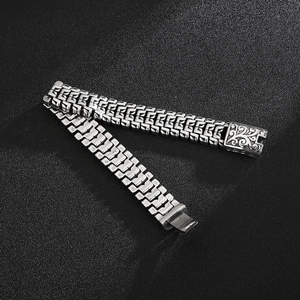 Detail of silver mechanical link steel bracelet featuring ornate floral engraving on the clasp