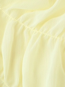 Detailed close-up of light yellow pleated chiffon fabric texture and stitching