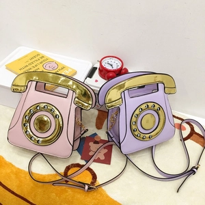 Close-up of pink and purple telephone-shaped crossbody bags with gold glitter finish