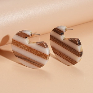 Detailed close-up of C-shaped earrings made of natural wood and ivory resin stripes