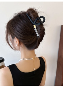 Gros plan d'une pince à cheveux noire mate ornée de perles, portée dans un style français