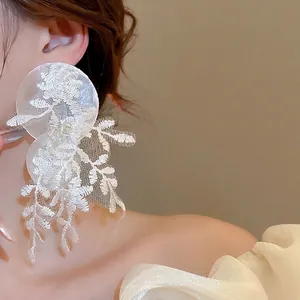Boucles d'oreilles fleur en dentelle avec coquillage en résine et pompon sur modèle