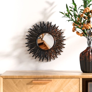 Detailed sunburst sun wall mirror with black frame and amber decorative stones on a wall