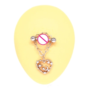 Macro detail of heart-shaped nipple ring with moon and star design in silver steel