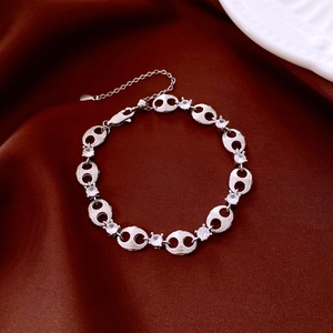 Detail of silver pig nose chain bracelet with zircon stones on dark silk background