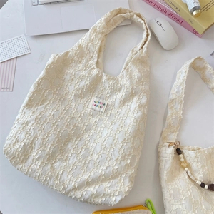 Close-up of textured floral lace tote bag with colorful logo tag on office desk