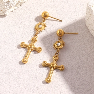 Détail de boucles d'oreilles en acier doré 18K avec pendentifs soleil et croix sur pierre