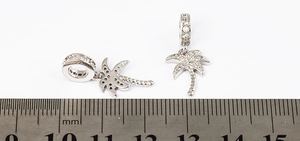 Detail view of gold plated palm tree pendants with micro-inlaid crystals and scale reference