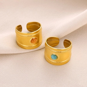 Detailed view of gold plated wide rings featuring center gemstones and woven relief edges