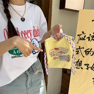 Détail d'un sac en toile jaune avec broderies et poignées tressées colorées