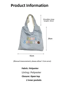 Detail view of light blue checkered canvas bag with colorful embroidery and size dimensions