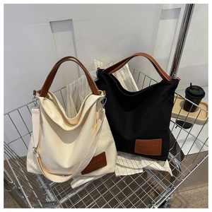 Detail of canvas tote bags in cream and black with leather handles in a shopping cart