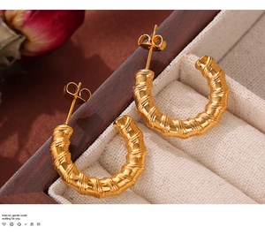 Close-up of gold C-shaped hoop earrings with bamboo texture on a vintage jewelry box