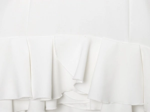 Close-up detail of white layered ruffles and high-quality woven fabric texture