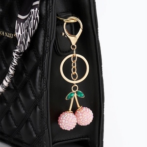 Luxurious pink rhinestone cherry keychain with green leaves on black quilted handbag