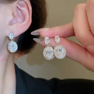 Macro detail of oval halo drop earrings with zircon in gold and silver finish
