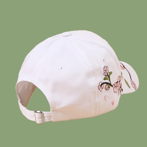 Detail of pink plum blossom embroidery on white cotton baseball cap with metal buckle