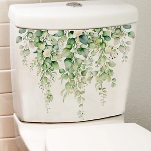 Close-up of green plant and white flower decals on a white ceramic toilet tank surface