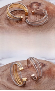 Detailed close-up of C-shaped twisted cable cuff bracelet with two-tone metallic finish