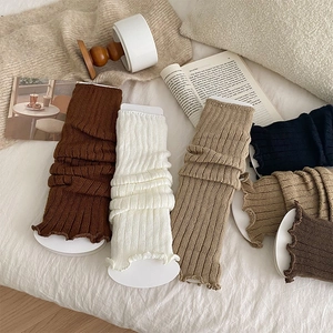 Detailed close-up of ribbed knit leg warmers in various colors on cozy white bedding