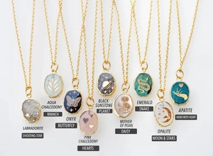 Flat lay of gold stainless steel necklaces with various natural stones and engraved motifs
