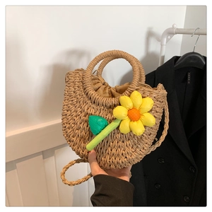 Detail der handgefertigten halbkreisförmigen Strohtasche mit großer gelber Sonnenblume