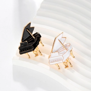 Elegant piano enamel brooches in black and white with gold finish on a display stand