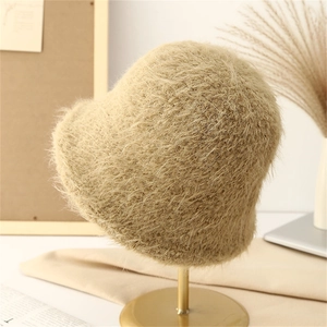 Detailed macro view of beige faux fur bucket hat material on a gold display stand