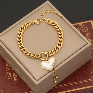 Gold Cuban link bracelet with heart pendant and delicate tassels on a vintage box