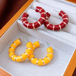 Detail of red and yellow enamel hoop earrings with gold bamboo texture segments
