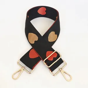 Detail of wide nylon bag strap with red heart jacquard and adjustable gold metal hooks