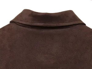 Détail du col d'une veste en daim marron foncé avec texture de couture apparente