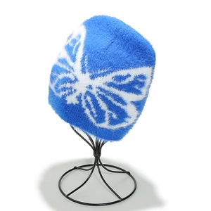 Dettaglio del berretto in maglia blu acceso con motivo a farfalla bianca jacquard