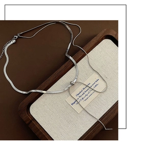 Macro shot of silver flat snake chain necklace with sliding ball and tassel in jewelry box