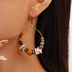 Detail of ethnic boho earrings with wooden beads and shell slices on female model