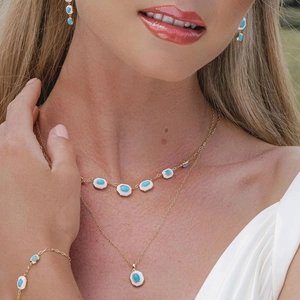Detail of a gold jewelry set with turquoise stones worn by a model in soft lighting