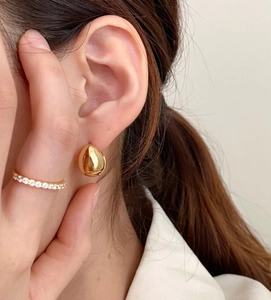 Close-up of elegant gold water drop stud earrings with high-polish mirror finish on model