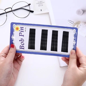 Black U-shaped bobby pins with ball tips for professional hairstyling on a simple card