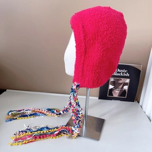 Detail of rose red fuzzy knit princess hat with colorful handmade long tassel accents